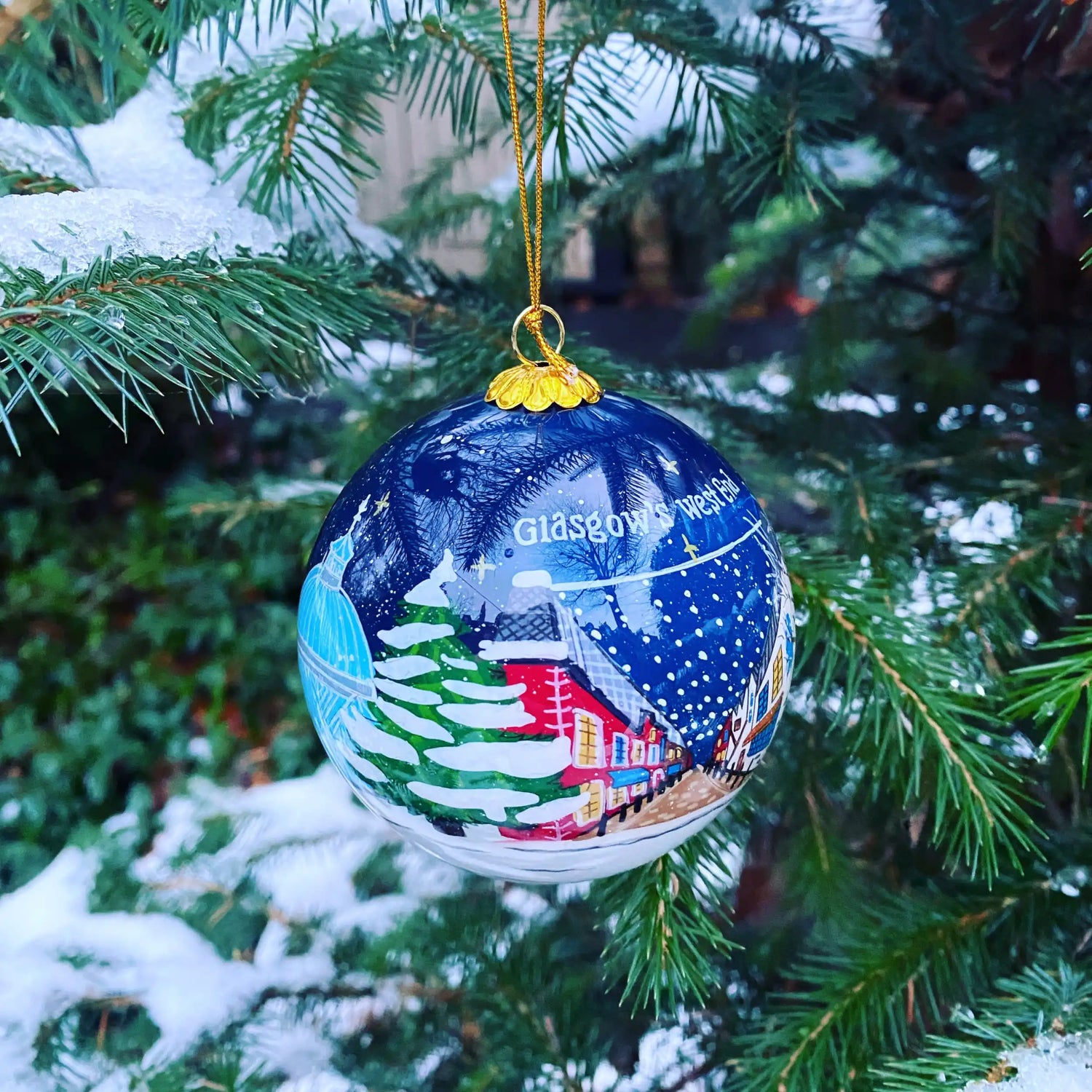 A blue Christmas ornament depicting a snowy village scene.