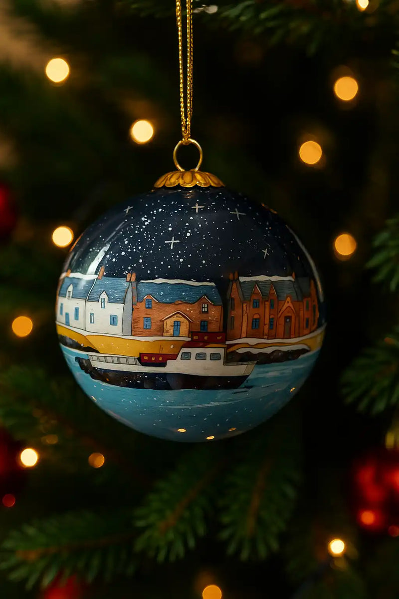 A dark blue Christmas ornament with a hand-painted snowy village scene.